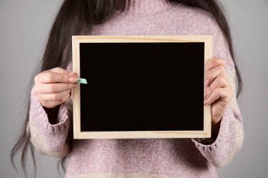 Tahta ya da karatahta tutan genç bir kadın