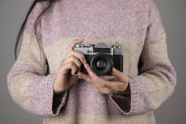 woman holding vintage camera on grey background