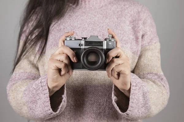 woman holding vintage camera on grey background