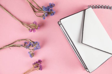 Masanın üzerinde kurumuş çiçek olan beyaz bir çanta.