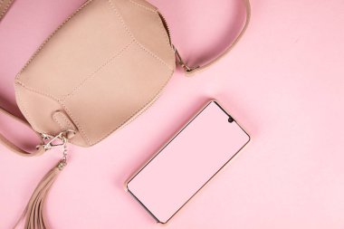 bag with smart phone on pink table