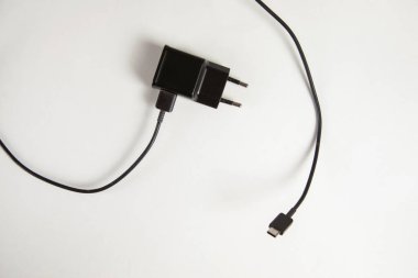 Beyaz arkaplanda cep telefonu siyah şarj cihazı 