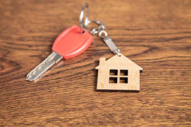 Ahşap arka planda izole edilmiş ev şekilli anahtarlık.