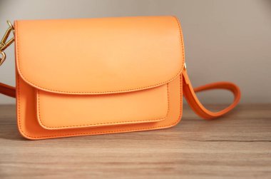 Ahşap masa arkasında turuncu bir çanta.