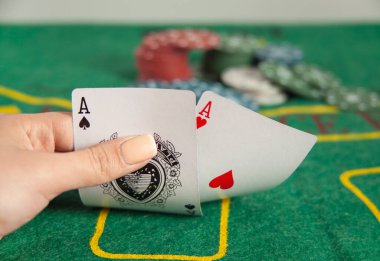 Elinde yeşil masada fişleri olan poker ası tutan bir kadın.