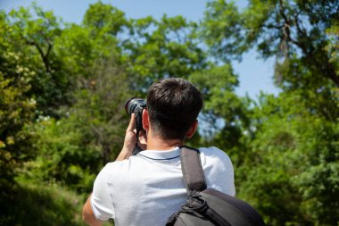 Genç gezgin adam dağda kamera tutuyor.
