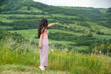 Mutlu kadın parmağı güzel dağı gösteriyor.