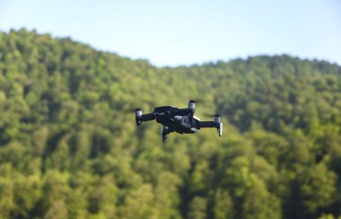 İHA yeşil ormanın üzerinde uçuyor.