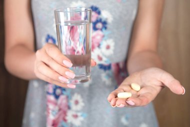 Genç bir kadın elinde bir bardak su ve uyuşturucu tutuyor.