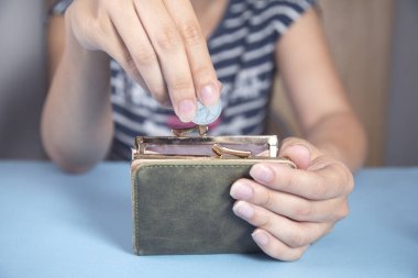 Elinde bozuk paralarla cüzdan tutan genç bir kadın.