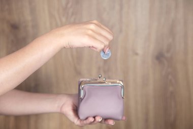 Elinde bozuk paralarla cüzdan tutan genç bir kadın.