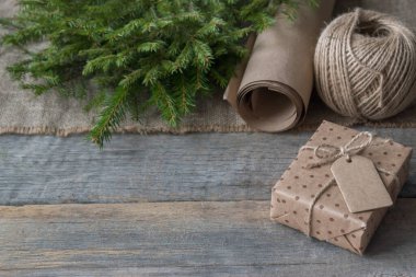 Ahşap bir arka planda hediye kutusu. İplik yumağı ve köknar dallarıyla sarma kağıdı