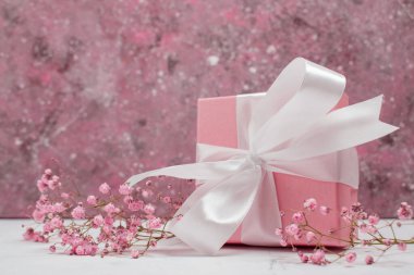 Pembe kurdeleli ve çingeneli hediye kutusu. Sevgililer günü, yıldönümü, anneler günü ve doğum günü kutlaması konsepti uzay boşluğunun bir kopyasına sahip.