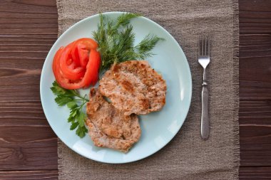 Tavuk ve sebzelerden oluşan bir yemek ahşap bir masada üst kattaki keten peçete görünümünde..