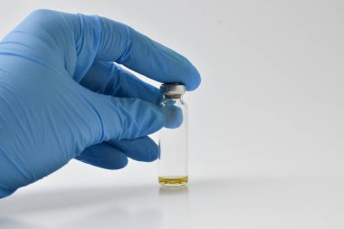 Mavi eldivenli bir el beyaz bir aşı şişesini izole eder. Boşluğu kopyala.