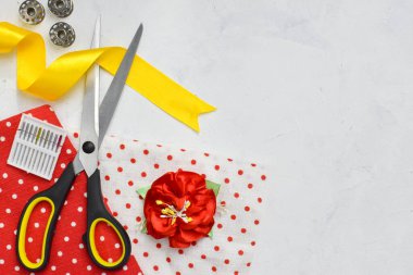 Çevrimiçi dikiş kursları. Dikişin arka planında kırmızı ve sarı tonlarda boşluğun bir kopyası var. Terzi kadın için çeşitli malzemeler. Düz yatıyordu. Üst görünüm.