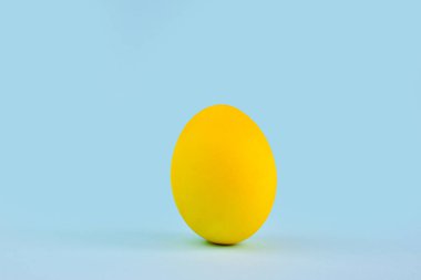 Mavi arka planda bir sarı yumurta. Mekanın kopyası. Paskalya. Minimalizm