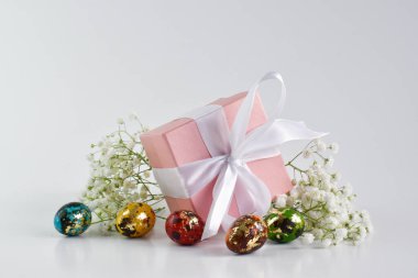 Paskalya 'nın asgari konsepti. Mekanın bir kopyası. Paskalya yumurtalarının yanında pembe fiyonklu hediye kutusu. Üst Manzara. Düz kaşık