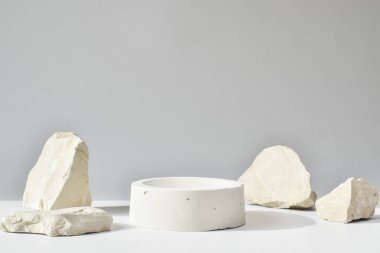Geometrik beton figürlü ve taşlı beyaz bir podyum. Çimento kutusu olan bir sahne. Asgari arkaplan.