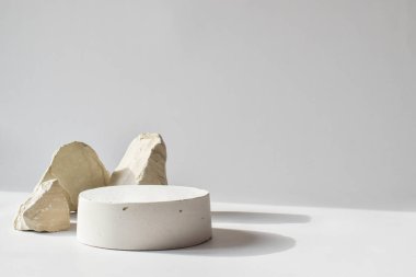 Geometrik beton figürlü ve taşlı beyaz bir podyum.