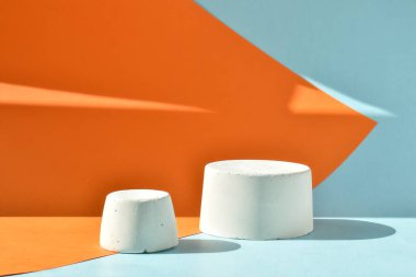 Podyum, betondan yapılmış geometrik bir figürle turuncu-mavi bir zemin. Çimentodan yapılmış bir vitrin sahnesi. Minimalist bir geçmiş. Kozmetik ürünleri sunumu.