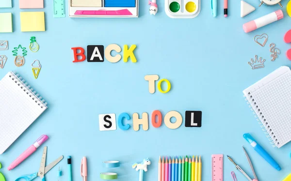 Un cadre fait de fournitures scolaires de couleur pastel sur un fond bleu clair, un endroit pour le texte. Fournitures de bureau. Je retourne à l'école. Il était allongé à plat. — Photo