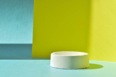 Podyum, betondan yapılmış geometrik bir figürle sarı-mavi bir zemin. Çimentodan yapılmış bir vitrin sahnesi. Minimalist bir geçmiş. Kozmetik ürünleri sunumu.