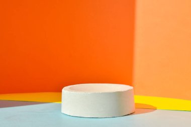 Podyum, betondan yapılmış geometrik bir figürle sarı-turuncu bir zemin. Çimentodan yapılmış bir vitrin sahnesi. Minimalist bir geçmiş. Kozmetik ürünleri sunumu.
