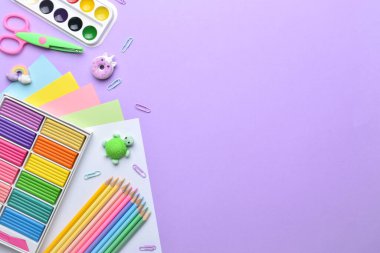 Mor bir arka planda pastel renkli okul malzemeleri çerçevesi, metin için bir yer. Düz düzen, üst görünüm, kopyalanacak bir yer.