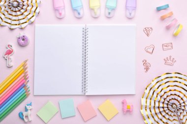 Açık bir not defteri, açık pembe arka planda, açık pembe renklerde okul gereçleri arasında, metin için bir yer. Ofis malzemeleriyle dolu bir geçmiş. Okula dönelim. Düz düzen, üst görünüm, kopyalanacak bir yer.