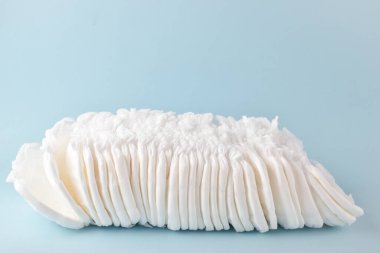 Açık mavi arka planda tek kullanımlık çocuk külotu yığını var..