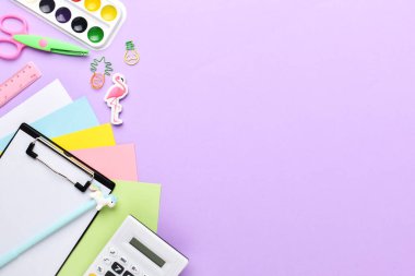 Mor bir arka planda pastel renkli okul malzemeleri çerçevesi, metin için bir yer. Düz plan, üst manzara, kopyalayacak bir yer. Okula geri dön.