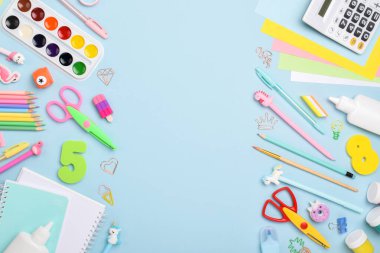Düz ofis malzemeleri. Açık mavi arka planda çeşitli kırtasiyeler. Okula dönelim. Okul aksesuarlarından yapılmış bir çerçeve.