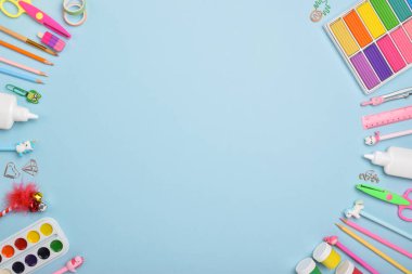 Düz ofis malzemeleri. Açık mavi arka planda çeşitli kırtasiyeler. Okula dönelim. Okul aksesuarlarından yapılmış bir çerçeve.