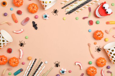 Turuncu arka planda çeşitli tatlılar ve mesaj için bir yer. Cadılar Bayramı için arka plan. Düz düzen, üst görünüm, kopyalanacak bir yer.