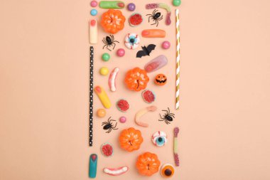 Turuncu arka planda çeşitli tatlılar ve mesaj için bir yer. Cadılar Bayramı için arka plan. Düz düzen, üst görünüm, kopyalanacak bir yer.