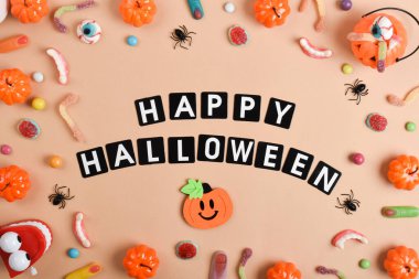 Turuncu arka planda çeşitli tatlılar ve mesaj için bir yer. Mutlu Cadılar Bayramı. Düz düzen, üst görünüm, kopyalanacak bir yer.