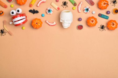 Turuncu arka planda çeşitli tatlılar ve mesaj için bir yer. Cadılar Bayramı için arka plan. Düz plan, üst manzara, kopyalayacak bir yer. Mutlu Cadılar Bayramı.