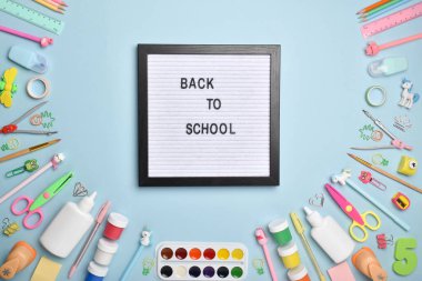 Düz ofis malzemeleri. Okula dönelim. Açık mavi arka planda keçeli tahtası olan çeşitli ofis malzemeleri. Düz düzen, üst görünüm, kopyalanacak bir yer.