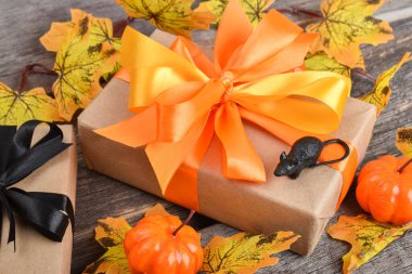 Cadılar Bayramı için turuncu kurdeleli hediye kutusunun yakın çekimi. Cadılar Bayramı için balkabakları ve hediyelerle dolu ahşap bir arka planda neşeli bir kompozisyon. Üst Manzara. Boşluğu kopyala