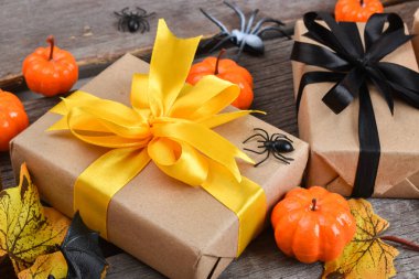 Cadılar Bayramı için turuncu kurdeleli hediye kutusunun yakın çekimi. Cadılar Bayramı için balkabakları ve hediyelerle dolu ahşap bir arka planda neşeli bir kompozisyon. Üst Manzara. Boşluğu kopyala