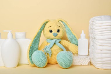 Çocuk hijyenine yakın çekim. Bebek bezi ve kozmetik ürünleri. Sarı bir tavşan ve çeşitli banyo aksesuarları..
