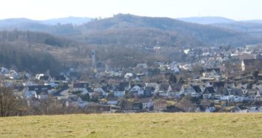 Kışın gökyüzünün altındaki dağ yamacında geniş yeşil sık bir orman.