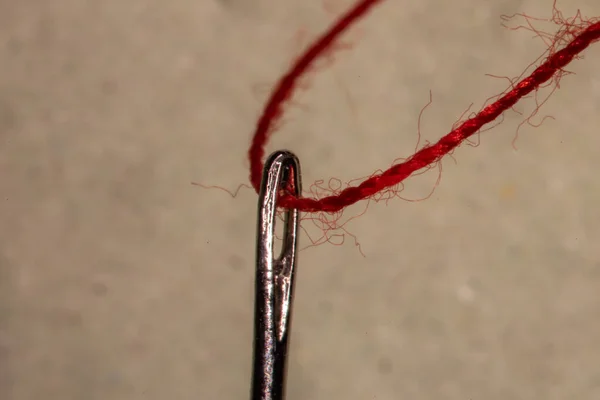 a red thread is threaded into a sewing needle