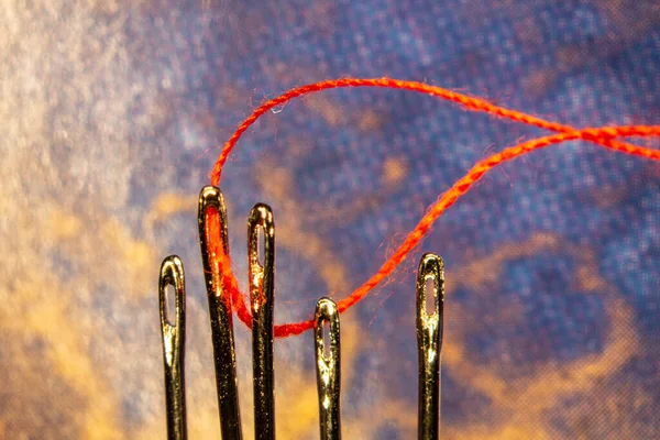 a red thread is threaded into a sewing needle