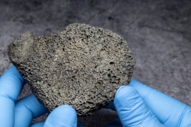 Bilim adamı koyu gri ay kayalarını inceliyor.