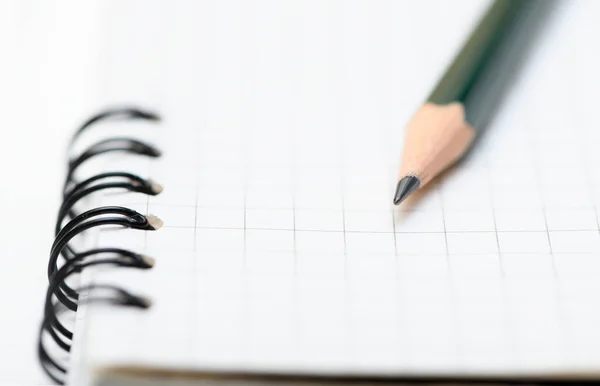 lead pencil is on blank page of the notebook. Selective focus on the tip of a pencil.