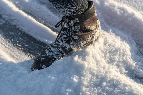Woman lag in boot glides on ice covered with snow.