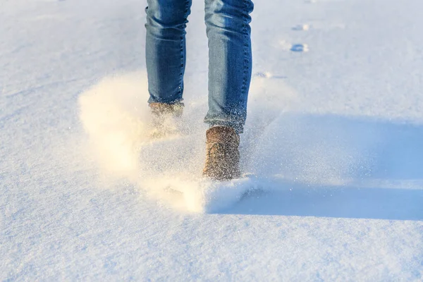 Woman lag in boot glides on ice covered with snow.
