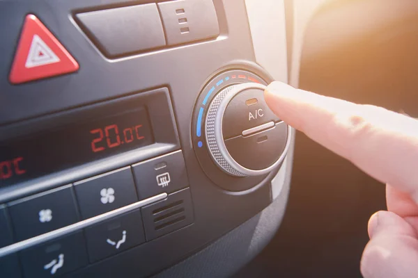 Man hand switches on the air conditioning in the car. Driver turning on car climate control system. travel by car. Close up view with selective focus.